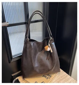 Close-up of deep brown tote bag with H.SHAN logo and creative baseball charm accessory