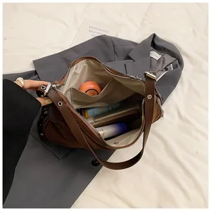Spacious interior of brown suede shoulder bag showing pockets for phone and cosmetics