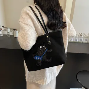 Black tote bag with 3D cat embroidery and blue fish detail shown on a model