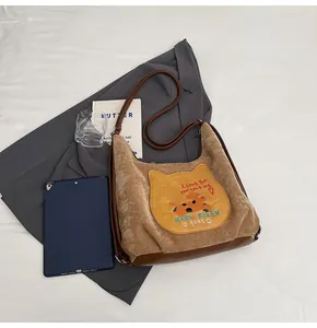 Détail du sac cabas en velours marron avec patch chat et finitions en cuir élégantes