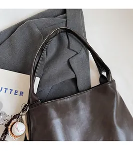 Detail of mocha brown leather tote bag with a baseball glove charm and comfortable strap