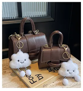 Detail view of dark brown textured leather handbags set with cute cloud charm on desk