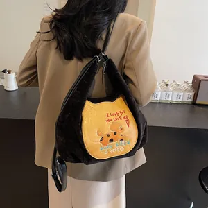Sac fourre-tout rétro en velours marron avec écusson chat sur un mannequin dans un café