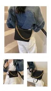 Detail of minimalist black leather shoulder bag with bold gold chain and leather strap