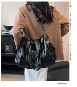 Détail du grand sac cabas noir avec doubles poignées et poche latérale sur un modèle