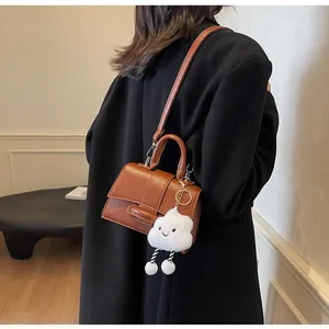 Brown vintage leather shoulder bag featuring a cute white cloud pendant on a model