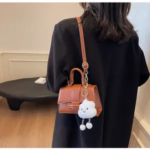 Brown vintage shoulder bag with cute cloud plush charm and adjustable strap worn by a model