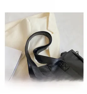 Détails de l'anse du sac en cuir noir avec coutures croisées et boucles métalliques