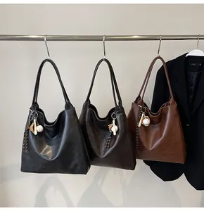 Three textured tote bags in black, coffee, and tan brown with decorative bag charms