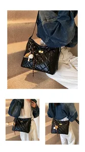 Détail du sac matelassé noir avec fermoir rotatif doré et pendentifs décoratifs