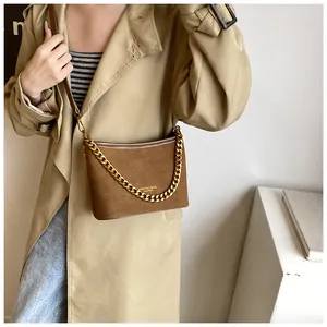 Detail of brown faux suede bucket bag with gold chain and leather shoulder strap