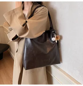 Detail of mocha brown tote bag with leather texture and baseball glove charm