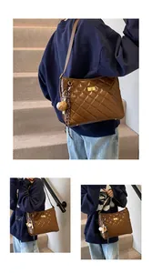 Gros plan du sac bandoulière en cuir matelassé marron foncé avec fermoir doré et ours
