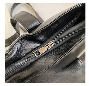Gros plan sur la fermeture éclair lisse et le cuir noir grainé de ce sac cabas