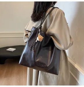 Close-up of deep brown tote bag featuring H.SHAN embossed logo and baseball charm detail