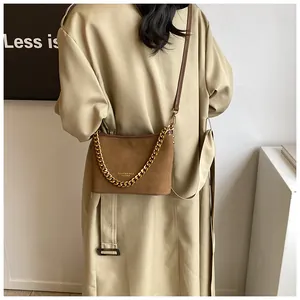 Close-up of brown suede bucket bag featuring gold chain strap and leather shoulder strap