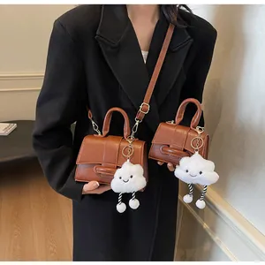 Detail of vintage brown leather handbags in two sizes with cute plush cloud charm