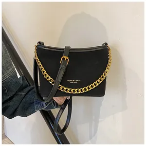 Detail of black suede bucket bag with bold gold chain and fashion leather lettering