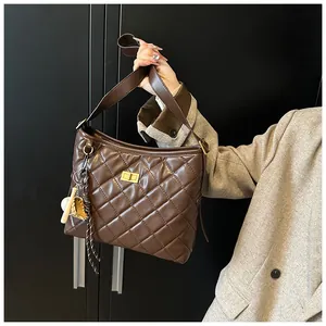 Vue détaillée de la texture cuir matelassé marron et du fermoir en métal doré du sac