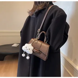Brown vintage leather shoulder bag with cute cloud charm shown on model in black coat