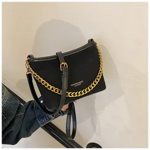 Detail of black bucket bag featuring thick gold chain strap and textured fabric finish