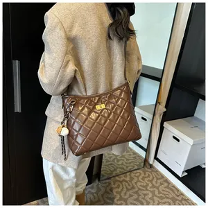 Détail d'un sac bandoulière matelassé marron foncé avec fermoir doré et pendentif