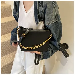 Detail of black bucket bag with golden chain strap and adjustable leather shoulder strap