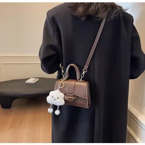 Detail of dark brown leather crossbody bag with a cute white cloud plush pendant