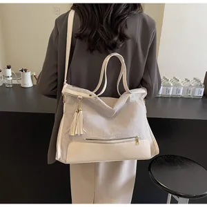 Détail du grand sac cabas avec pompon porté par un mannequin dans un café chic