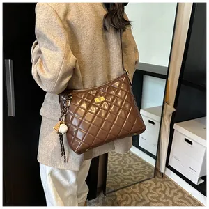 Détail d'un sac bandoulière marron matelassé avec fermoir doré et charme baseball