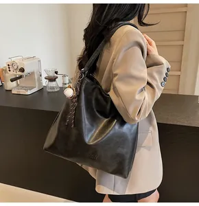Close-up of black leather tote bag with H.SHAN embossing and baseball bat pendant charm