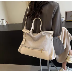 Sac fourre-tout en toile et cuir avec pompon présenté dans un intérieur moderne