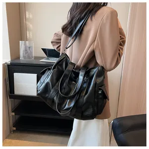 Détail du grand sac cabas noir en similicuir souple plissé avec des poches latérales