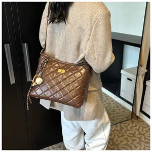 Détail d'un sac bandoulière matelassé marron avec fermoir doré et pendentif baseball