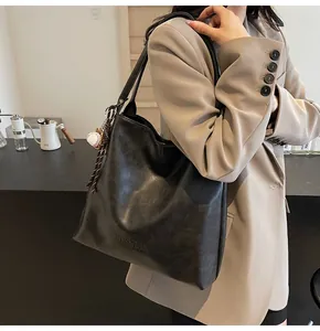 Macro detail of black leather tote bag featuring H.SHAN logo and white baseball charm