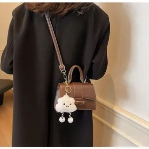 Brown vintage shoulder bag with cute cloud charm shown on a model in long coat