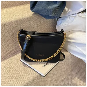 Close-up of black bucket bag with gold chain strap and fashion lettering on suede texture