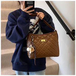 Détail du sac hobo matelassé marron foncé avec fermoir doré et pendentif de sport chic
