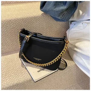 Detail of black bucket bag with gold chain strap and textured fabric on street steps