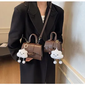 Detail of vintage brown leather satchel set with metal hardware and cloud plush charm