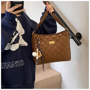 Détail du sac bandoulière matelassé marron avec fermoir doré et breloque baseball