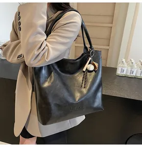 Close-up of black leather tote bag featuring H.SHAN embossed logo and baseball charm detail