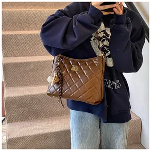 Détail du sac matelassé marron foncé avec fermoir doré et pendentifs élégants