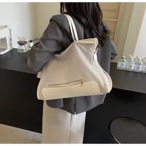 Détail du sac fourre-tout en toile et cuir avec poche zippée à l'avant et pompon