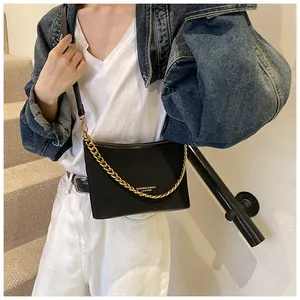 Detail of black bucket bag with chunky gold chain and leather shoulder strap on model