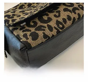 Detailed view of leopard jacquard fabric and black leather stitching with fine sewing