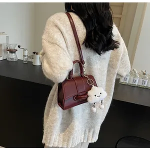Deep red leather shoulder bag with cloud charm shown on model in cozy sweater
