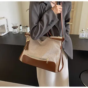 Détail du sac cabas en toile avec garniture en cuir marron et pompon au bar à café