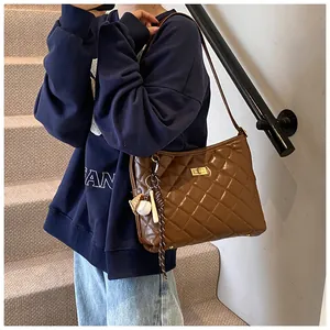 Sac à bandoulière matelassé marron avec fermoir doré et breloque baseball sur mannequin