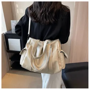 Vue détaillée du grand sac cabas beige avec poches latérales et bandoulière réglable